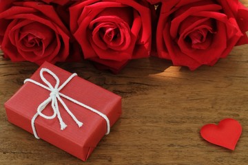 Lovely blooming red color rose flower and elegant gift box on wood table background decorated with mini red heart figure, sweet valentine present concept