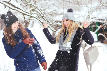 funny and happy two beautiful girlfriends play in the snow in winter, a lot of snow and winter clothes. blonde and brunette emotions