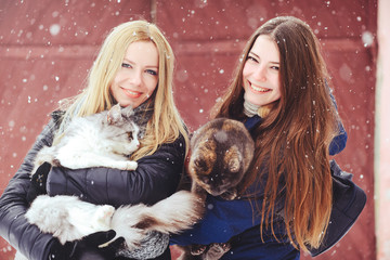 two beautiful girls with big cats in the winter outside, animal protection, fun in nature