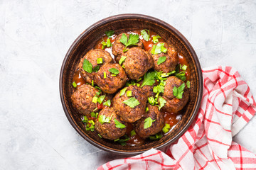 Meatballs in tomato sauce on light stone table top view. 