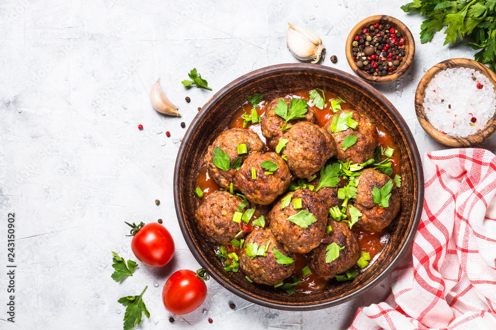 Sticker meatballs in tomato sauce on light stone table top view.