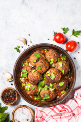 Meatballs in tomato sauce on light stone table top view. 