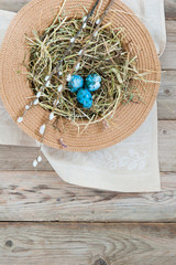 Nest in a wicker hat and painted spotted Easter eggs with spring flower. Empty space for text
