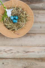 Nest in a wicker hat and painted spotted Easter eggs with flower. In the top left corner. Text space