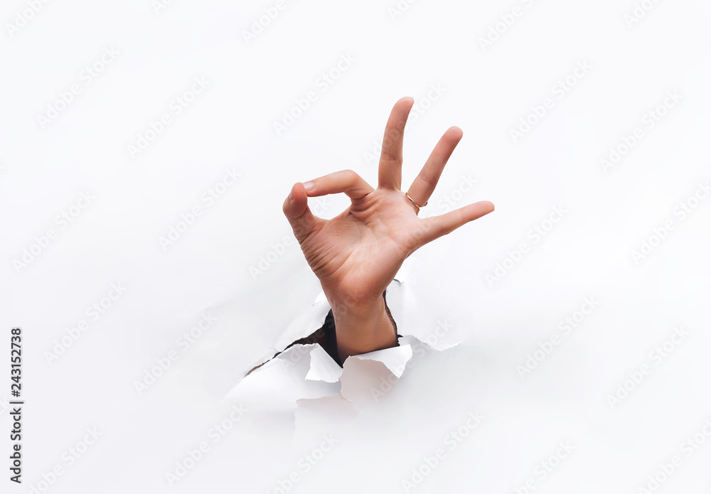 Wall mural hand ok sign. the hand came out into the hole and shows symbol of fine. copy space.