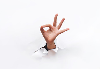 Hand ok sign. The hand came out into the hole and shows symbol of fine. Copy space.