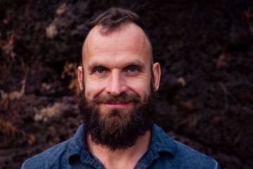 Fototapeta premium Handsome man with beard. Close up portrait of stylish bearded hipster on stoun roks beach background. Attractive young person toothy smile face beard festival. shaving idea.