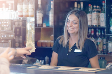 The waiter girl receives a tip from the client at the hotel bar. The girl is happy with luck. A bartender woman is happy to receive a tip at work. Emotions. The concept of service. Toning