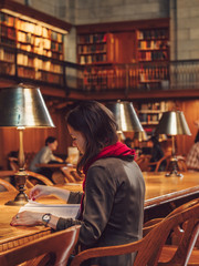 Young woman reading a book in the library