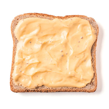 Bread slice with mustard sauce isolated on white, clipping path. Slice of multigrain bread square form plaster mustard sauce for toast. Image of one slice wholegrain bread, top view or flat lay.
