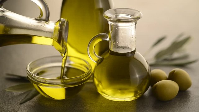 Organic olive oil. Bottle of Extra virgin oil pouring in to glass bowl