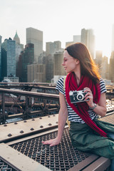 Fototapeta na wymiar Smiling girl with a camera on Brooklyn Bridge