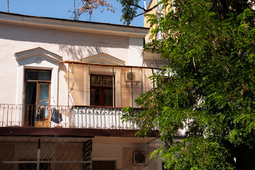 Old historic stone house on the yard with trees around. Old city buildings before and after restavration. Ancient windows, roofs, balconies. sculptures, walls  South, summer 