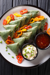 Indian cuisine Spinach samosa served with vegetables and two sauces close-up on a plate. Vertical top view