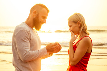 Romantic marriage proposal at the seaside at sunset on the beach sea. Young couple in love female said yes to offer of marriage February 14, St. Valentine's Day