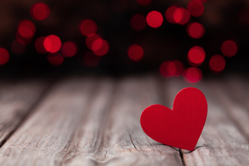 Red wooden heart against bokeh background for Valentines day card.