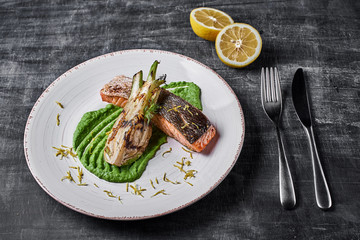 Baked salmon steak with mashed green peas , caramelized onions and lemon