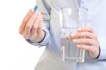 Blue capsule pill and glass of water medicine in woman hand on white background, pharmacy concept