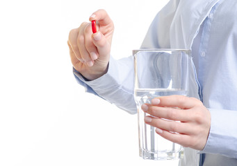 Red capsule pill and glass of water medicine in woman hand on white background, pharmacy concept