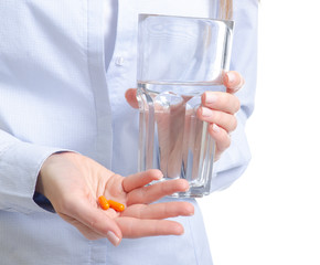 Orange capsule pill and glass of water medicine in woman hand on white background, pharmacy concept