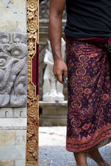 Balinese man in traditional sarong enters a temple
