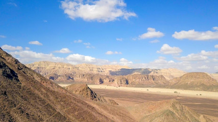 Desert landscape - Aerial image of mountains and dry land with blue cloudy sky in the background.