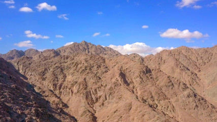 Desert landscape - Aerial image of mountains and dry land with blue cloudy sky in the background.
