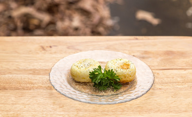 Air Fried Free Range Organic Eggs:  Two air fried free rage organic eggs on a glass plate with fresh parsley garnishment, all on a wooden tray.