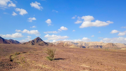 Desert landscape - Aerial image of mountains and dry land with blue cloudy sky in the background.