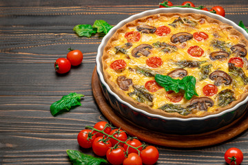 Baked homemade quiche pie in ceramic baking form on concrete background