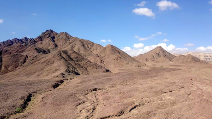 Desert landscape - Aerial image of mountains and dry land with blue cloudy sky in the background.