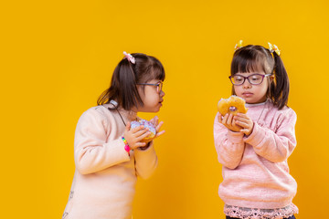 Interested little girls with down syndrome observing their donuts