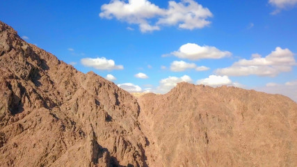 Desert landscape - Aerial image of mountains and dry land with blue cloudy sky in the background.