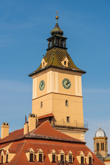 Fototapeta na wymiar Tower clock of the Council House building in Brasov, Transylvania on a blue sky background, situated in the historic Council Square - Piata Sfatului. Baroque architecture landmark.