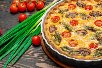 Baked homemade quiche pie in ceramic baking form on concrete background