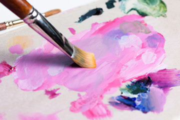 Obraz premium The artist squeezed the paint onto the palette and mixes the pink paint with a synthetic brush.