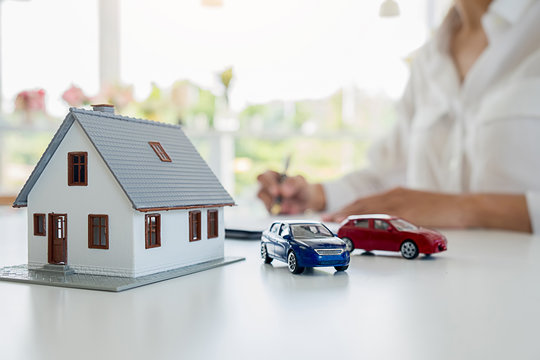 Car and House model with agent and customer discussing for contract to buy, get insurance or loan real estate or property background.