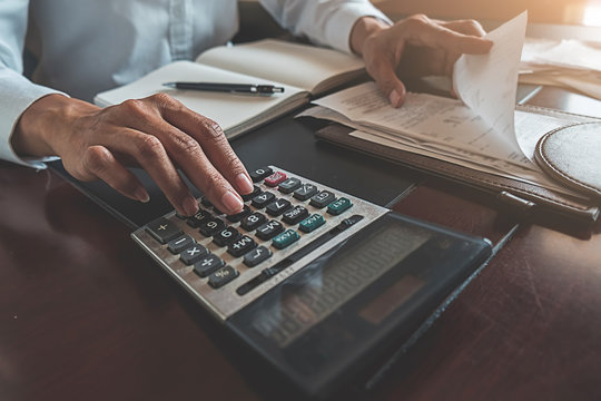 Woman with bills and calculator. Woman using calculator to calculate bills at the table in office. Calculation of costs.