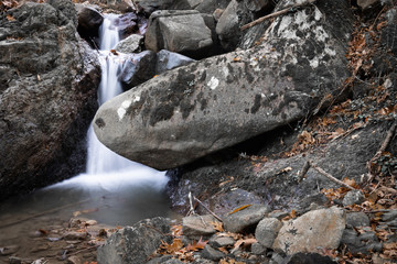 beautiful forest waterfall creek in long exposure in fall scenery
