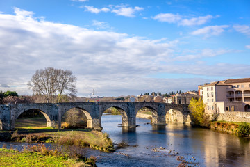 An old bridge crossing a calm river in Carcassonne in France in a blue sky day