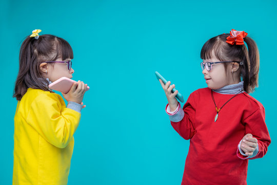 Two twin sisters with down syndrome carrying mobile phones - Powered by Adobe