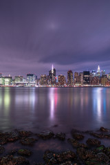 Fototapeta na wymiar View on Midtown manhattan from east river with rocks on foreground at night,long exposure shot