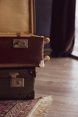 Two vintage open suitcases stand on wooden floor with carpet.