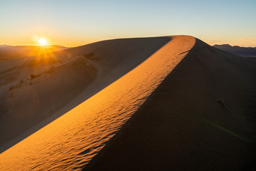 Wind carved ridge in a sand dune with the setting sun in the bcakground, Kelso Sand Dunes, Mojave National Preserve, California