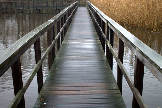 Old wooden bridge on the lake.Dry reed.January month. Winter.