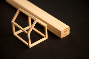 Miniature model of wood frame house with pile of wooden planks