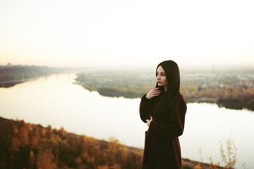 Strict brown-haired woman in the autumn park