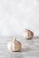 Two white vegetarian raw organic garlics on the marble table