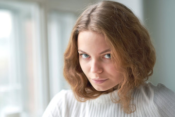 portrait of a beautiful curly girl. the mysterious face of a woman at the window.