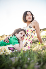 The boy and his mother are lying in the meadow.